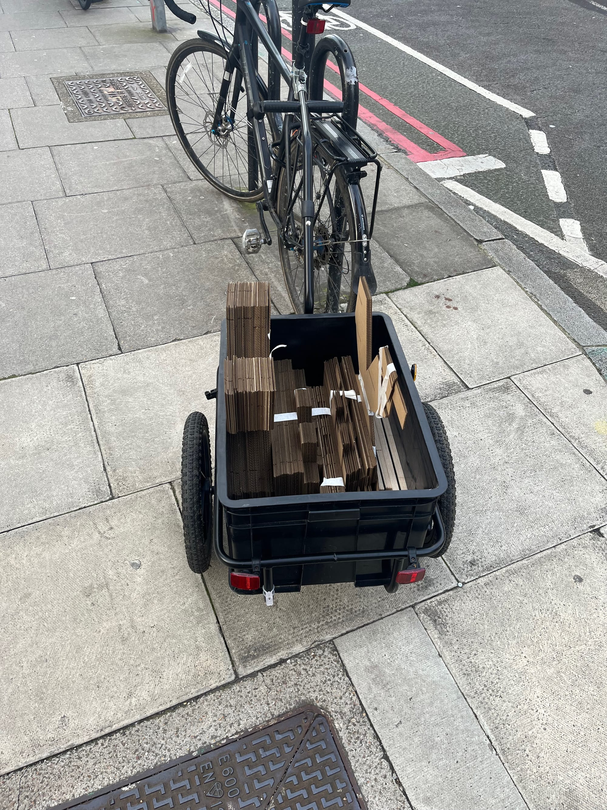 Photograph of bicycle trailer with \~50 sheets of material cut into pieces.